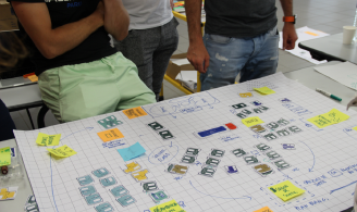 Photographie représentant un plan sur grand format papier pendant un atelier, avec des participants autour du plan 